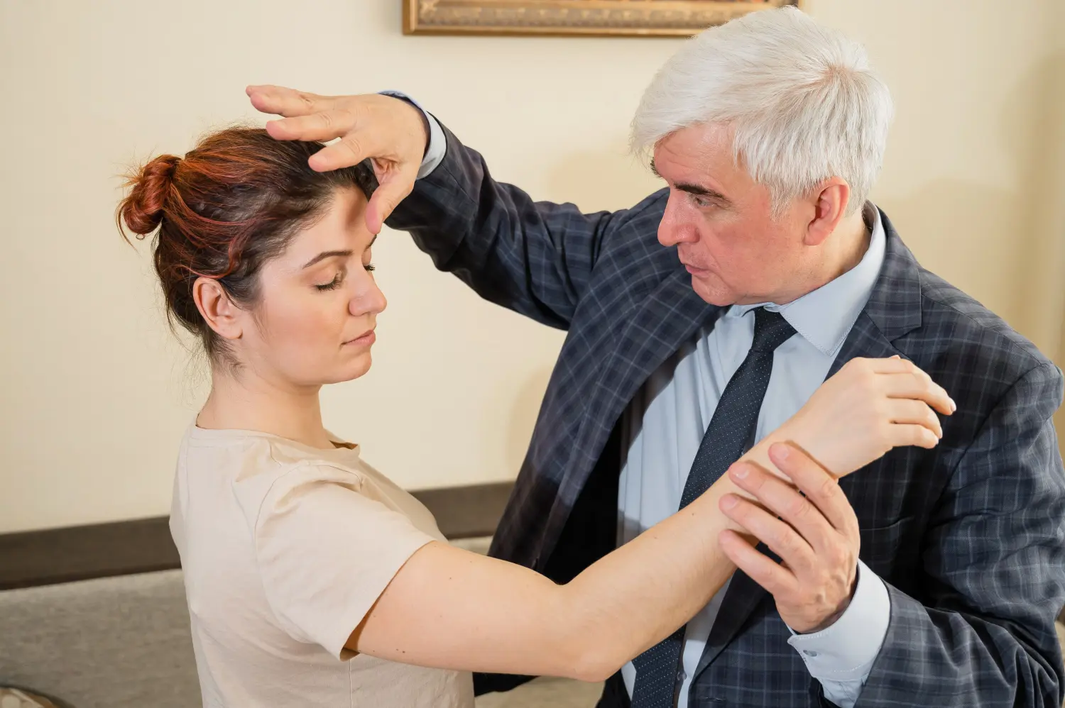 Reifer grauhaariger Mann hypnotisiert kaukasische Frau während einer Hypnotherapiesitzung.